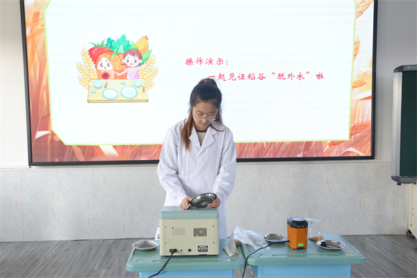 中储粮大连直属库:校企联动 共绘粮食安全“同心圆”_fororder_青穗志愿者为孩子们展示稻谷检验流程