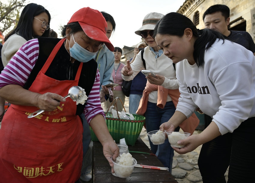 信阳市新县:古村糍粑香 民俗韵味长_fororder_游客品尝糍粑(焦汉平 摄)
