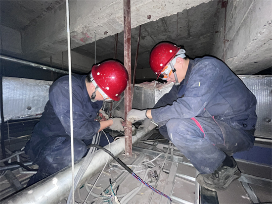 方大集团中兴商业暖通科：为消费者筑起“温暖屏障”_fororder_在狭小的棚顶里，中兴商业暖通科员工在聚精会神地检修设备-1 摄影：徐晨