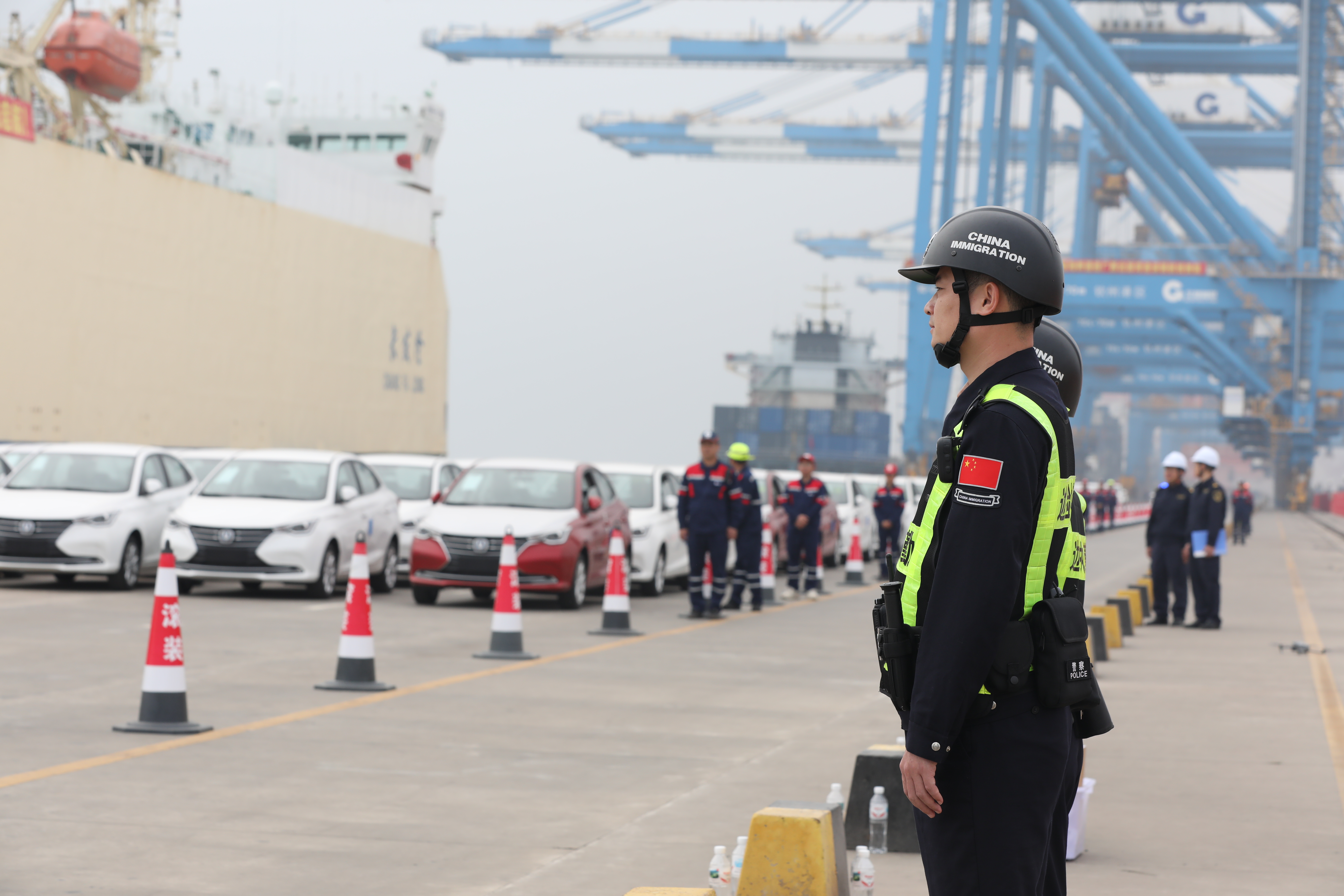 国产汽车乘“新通道”快车出海 边检跑出通关“加速度”_fororder_图为移民管理警察现场保障国产汽车安全通关.JPG
