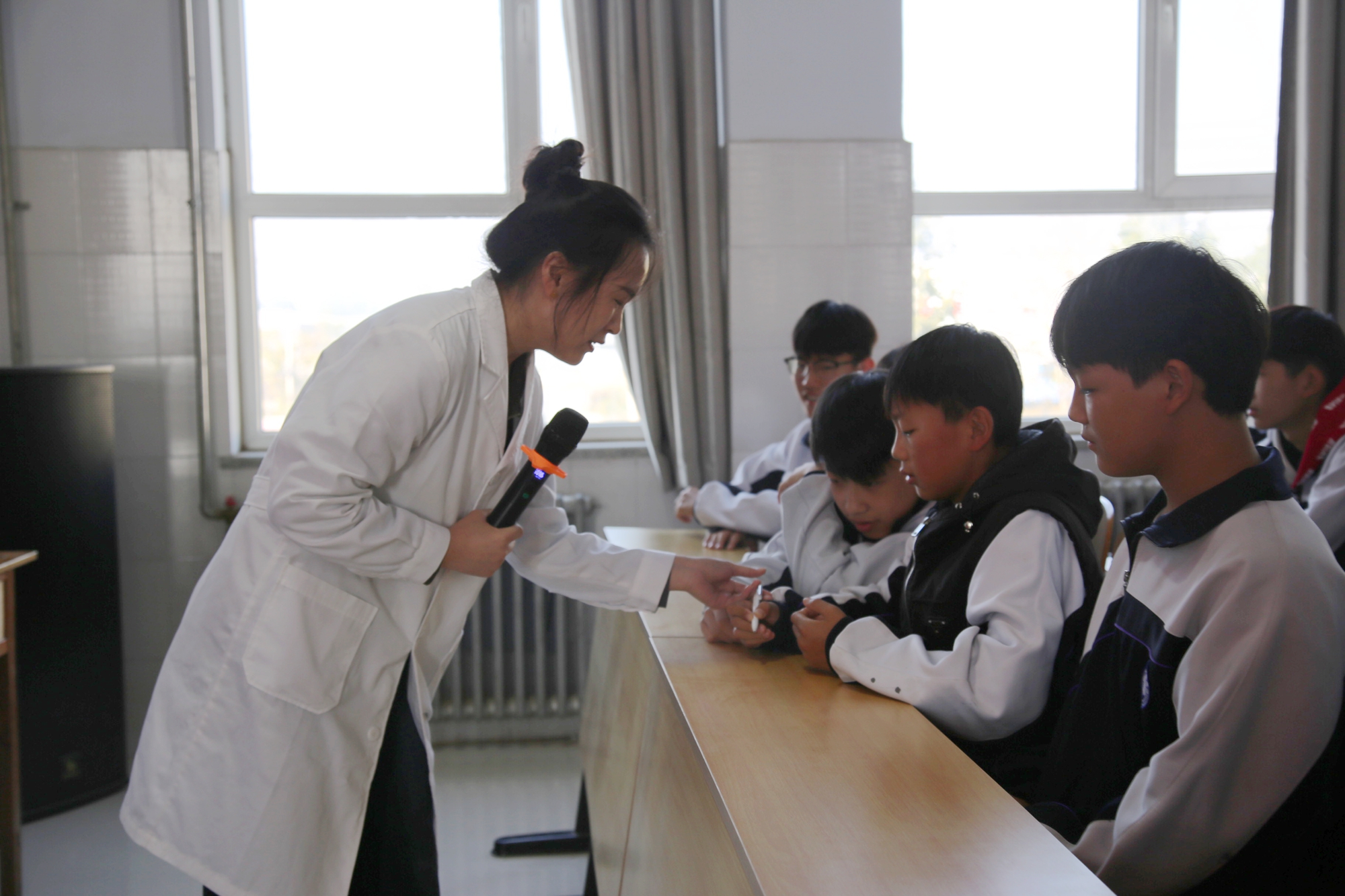 保定市满城区残联开展国际盲人节宣传活动_fororder_工作人员手把手纠正学生拿笔姿势 摄影 袁野.JPG