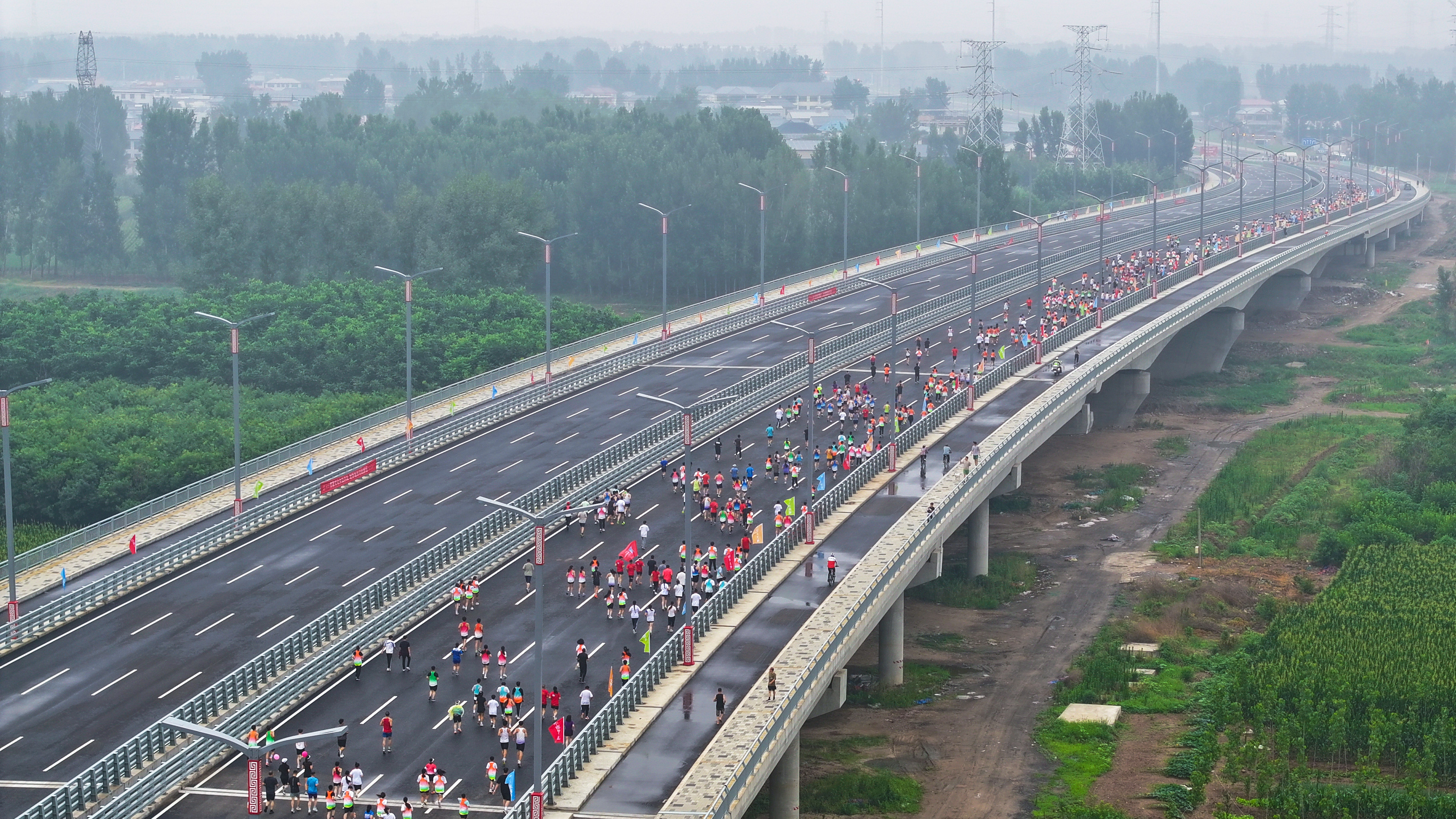 河北涿州：腾飞大街北延跨北拒马河大桥建成通车_fororder_7月1日，河北省涿州市腾飞大街北延跨拒马河大桥正式通车。图为市民在大桥上健康跑（航拍照片）。熊华明摄