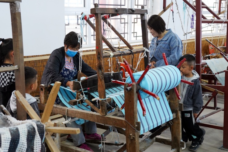 河北迁安融合创新点燃全域旅游新引擎_fororder_游客在迁安市绣娘非遗文化园感受传统手工织布技艺，韩春东 摄