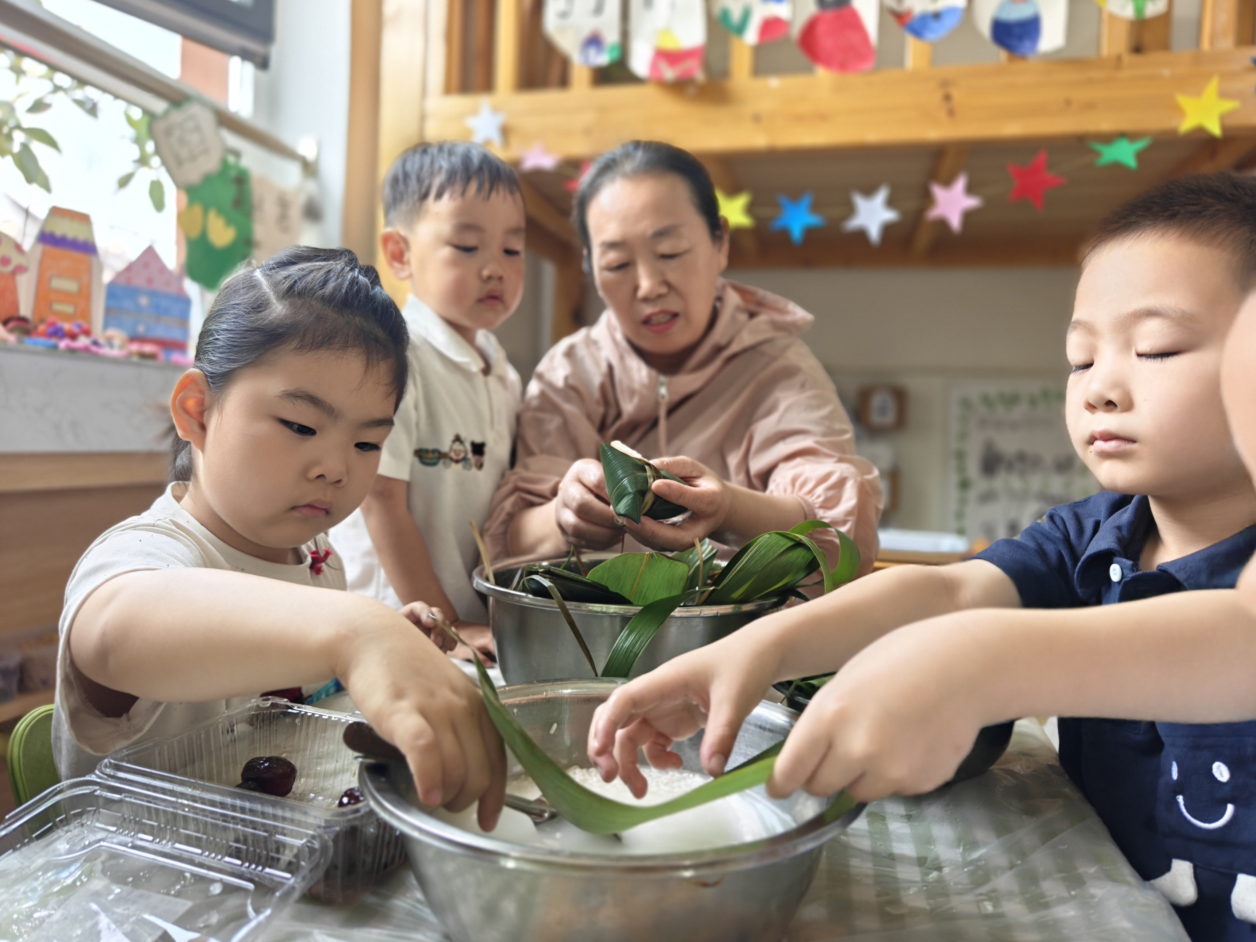 河北安国：粽叶飘香迎端午  多彩实践润童心_fororder_孩子们和家长志愿者一同包粽子  梁颖摄