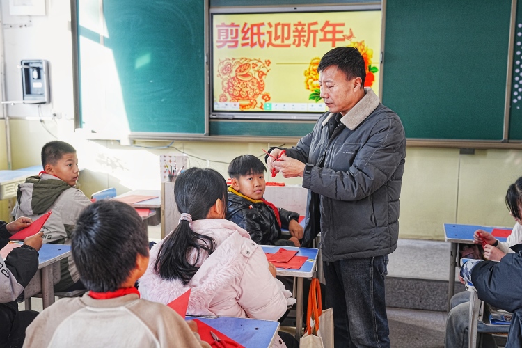 河北迁安：剪纸非遗进校园 指尖生花迎新年_fororder_12月25日，非遗传承人正在一对一指导学生剪纸。张泽慧摄