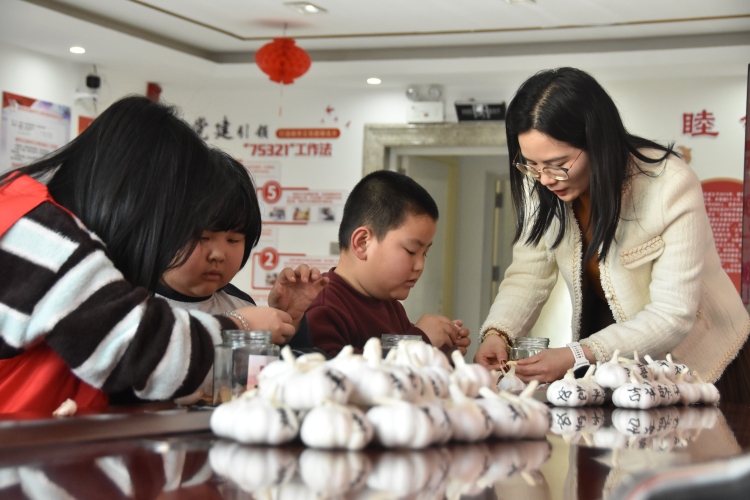 遵化市开展寒假爱心托管班活动_fororder_志愿者们带领小朋友们为制作腊八蒜做准备。许昊摄.JPG