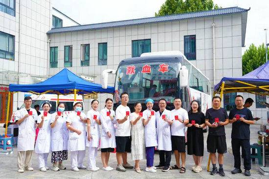 南阳市中医院：医者挽袖献热血 同心共筑生命防线_fororder_南阳市中医院医务工作者及职工在献血车前展示献血证 供图 南阳市中医院