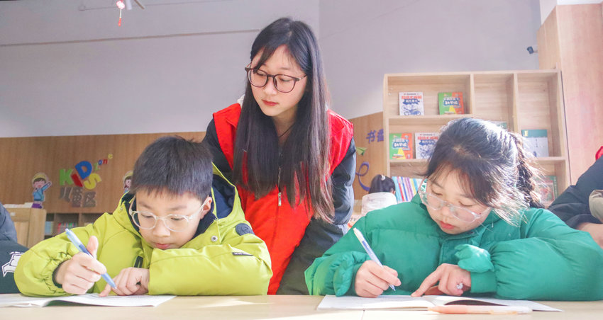 南阳市卧龙区启动公益爱心托管服务_fororder_返乡大学生志愿者在诸葛书屋里辅导小朋友们写作业.JPG