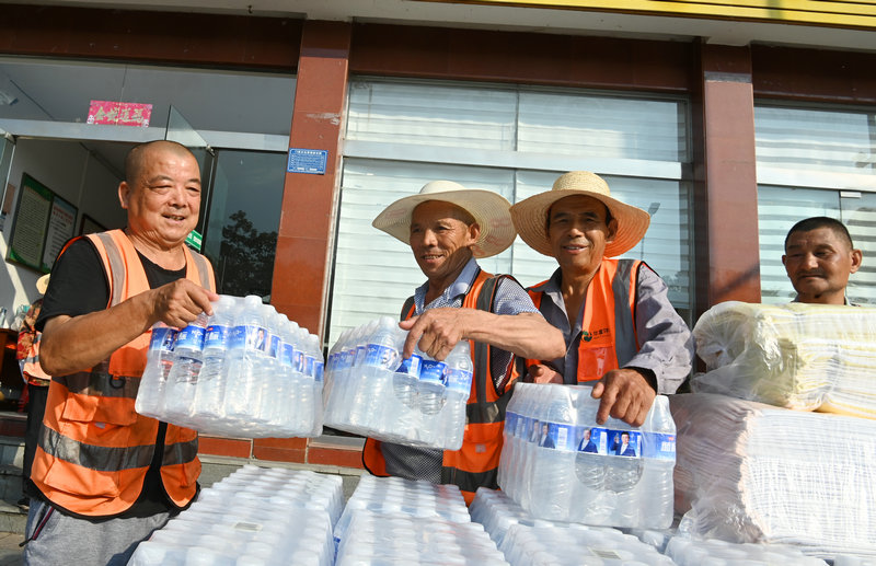 信阳市新县：夏日送清凉 关怀暖人心_fororder_正在搬运矿泉水等物品（焦汉平 摄）