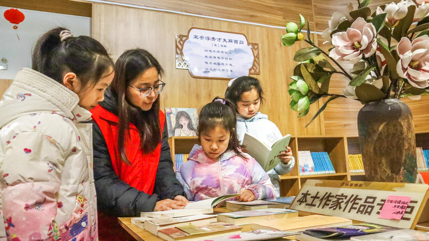 南阳市卧龙区启动公益爱心托管服务_fororder_返乡大学生志愿者在诸葛书屋里为小朋友讲解本土作家作品.JPG