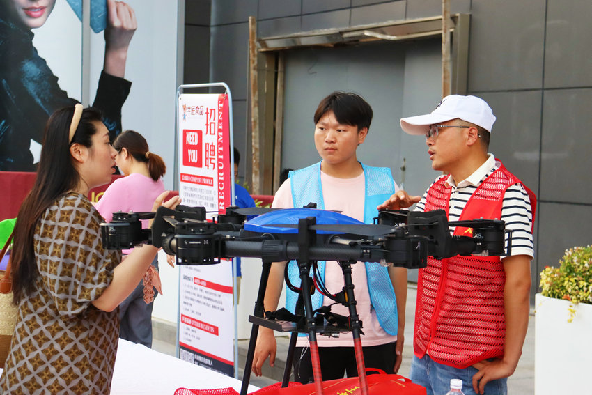 河南南阳：灯火璀璨处 夜市送岗来_fororder_求职者在一家无人机培训企业摊位前咨询招工情况.JPG
