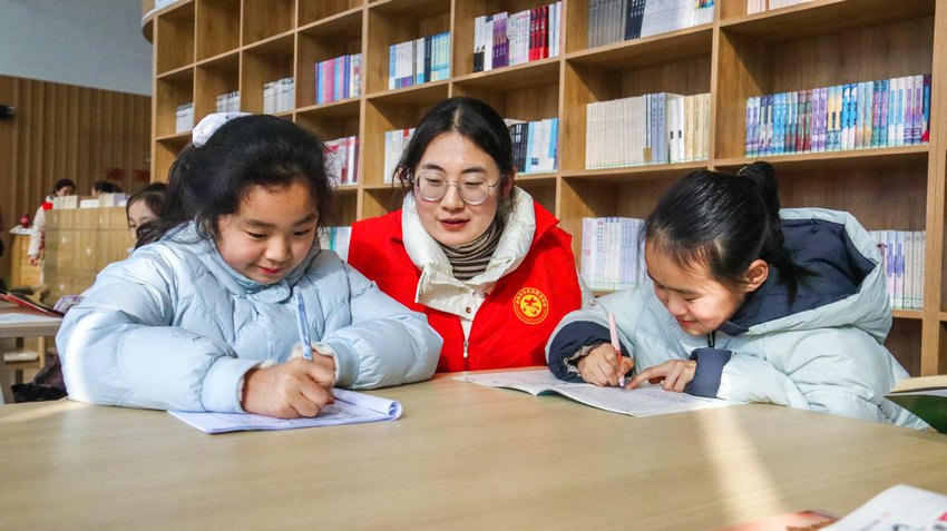 南阳市卧龙区启动公益爱心托管服务_fororder_小朋友在志愿者陪伴下写作业.JPG