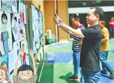 小学生变身小画家 爸爸们在200张卡通画像中找自己
