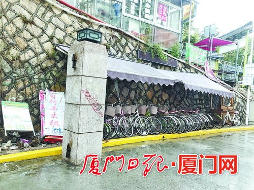【法治 主推】【滚动新闻】【地市 厦门】(摘要：记者来到厦大芙蓉隧道出口黄女士所说的自行车棚附近。发现设置在一处斜坡石壁下的紫色车棚已微微泛白，十几辆自行车歪歪斜斜地停在棚内，一旁写有“自行车出租”的广告牌倒在地上。走近一看，车把手、座椅上都覆盖了一层灰，车身锈迹斑斑，车轮里还有不少零食包装袋和纸杯。)厦大芙蓉隧道出口自行车棚无人管 人行道垃圾成堆