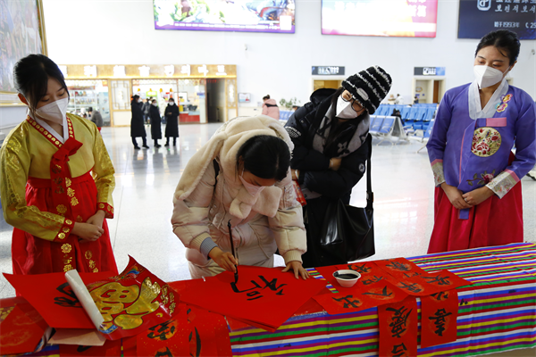 春运首日 延吉车务段温暖回家路_fororder_旅客现场书写福字和春联 供图 延吉市委宣传部