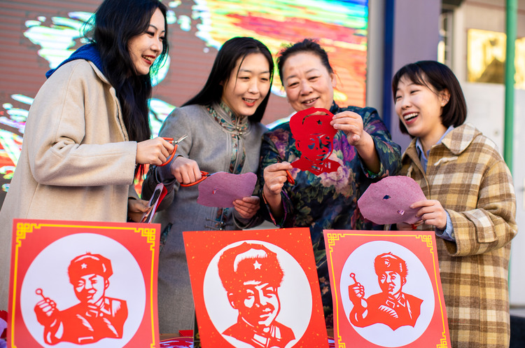 呼和浩特市玉泉区：寻雷锋足迹 扬志愿精神_fororder_6——2023年3月3日，呼和浩特市玉泉区清泉街社区志愿者，非遗剪纸传承人董存娥（ 右二）在展示创作的“雷锋”剪纸作品。20230303-A01I2945