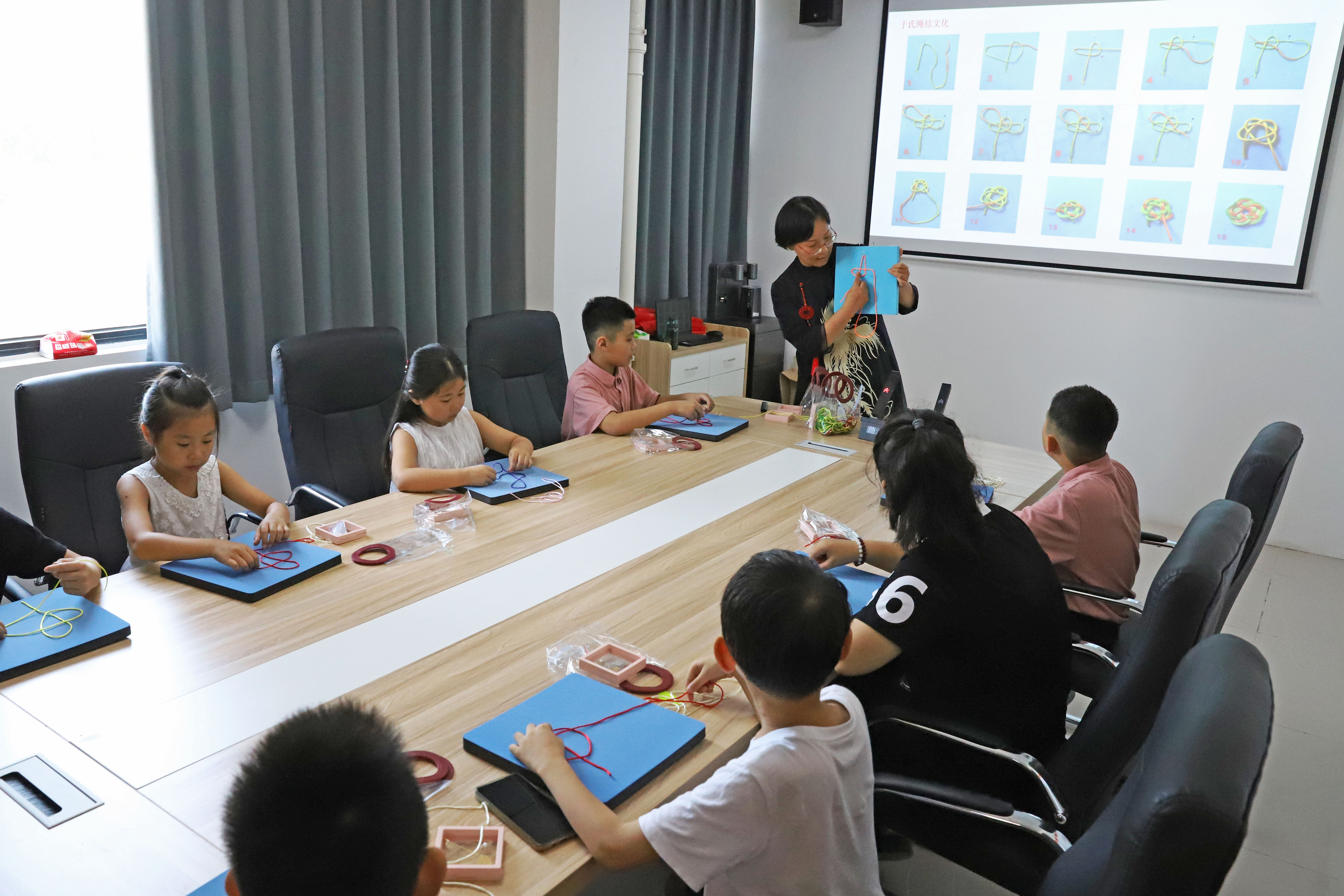 河北涿州：学生们假期生活增添“非遗色”_fororder_7月16日，涿州市非遗人传承人于长娟给学生们讲解绳结编织技艺。熊华明摄
