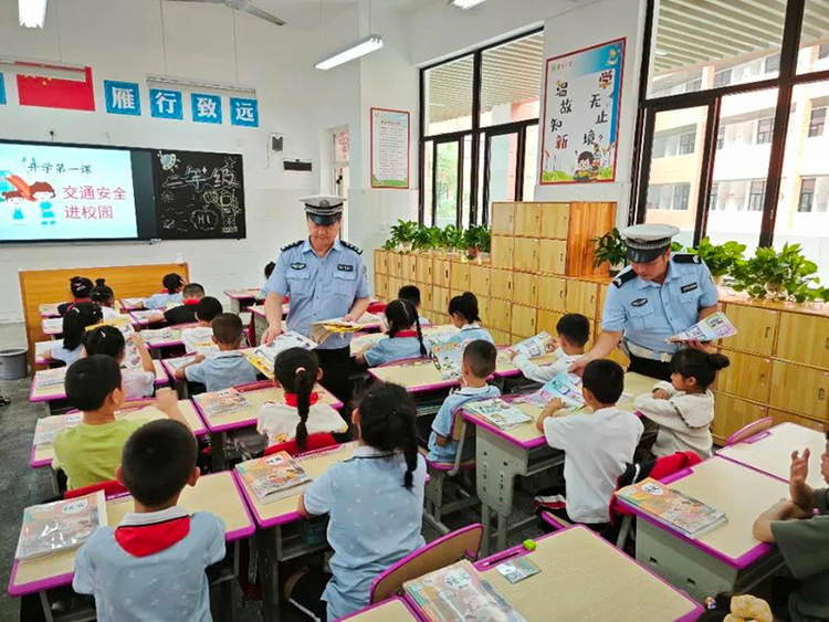 广汉公安站好“护学岗” 撑起“平安伞”_fororder_向学生发放交通宣传手册
