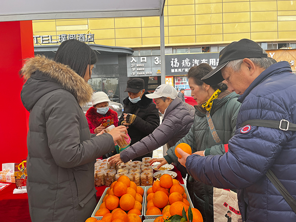 泸州市江阳区华阳街道西岸村乡贤们带着农特产品“赶大集”_fororder_向群众介绍板鸭等农产品