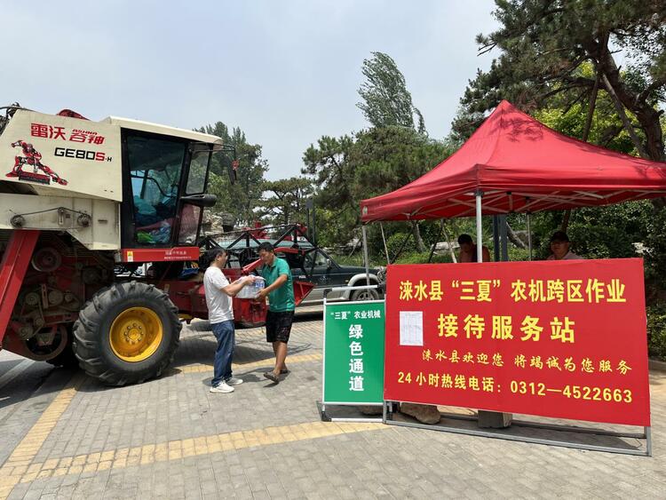 河北涞水：抢抓农时推进“三夏”生产_fororder_图为工作人员为跨区作业农机手送上防暑物资。（徐梓钰 摄）