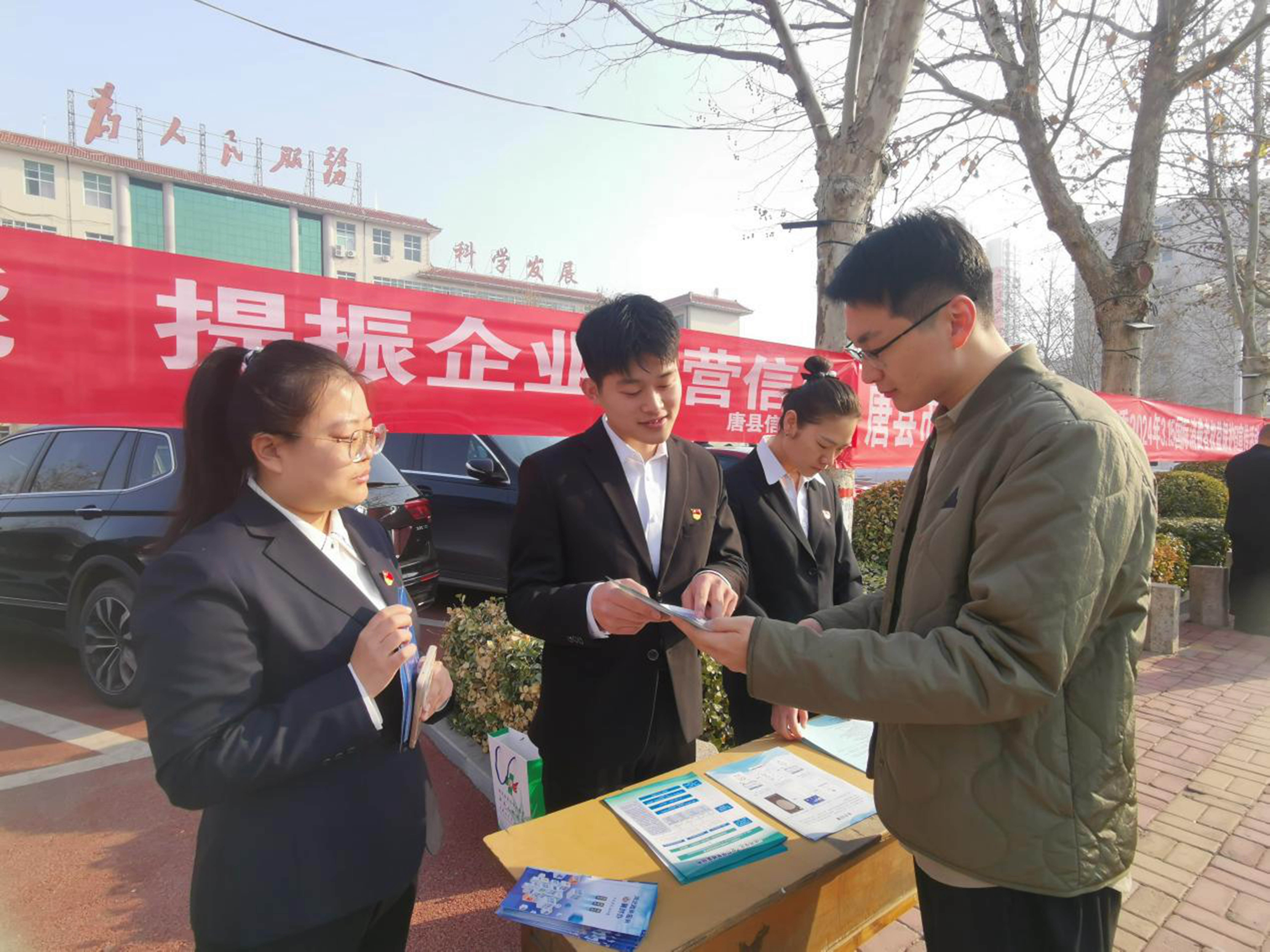 河北唐县：加快社会信用体系建设 打造信用高地_fororder_诚信宣传活动现场，工作人员向群众讲解宣传册