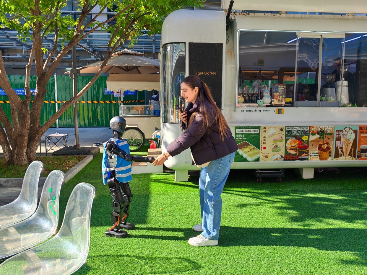 Regards de la Génération Z du Sud global sur Beijing : une jeunesse nouvelle dialogue avec la « Beijing traditionnelle » et la « vitalité nouvelle »_fororder_墨西哥网红博主在AI原点社区与机器人互动  摄影 曲畅