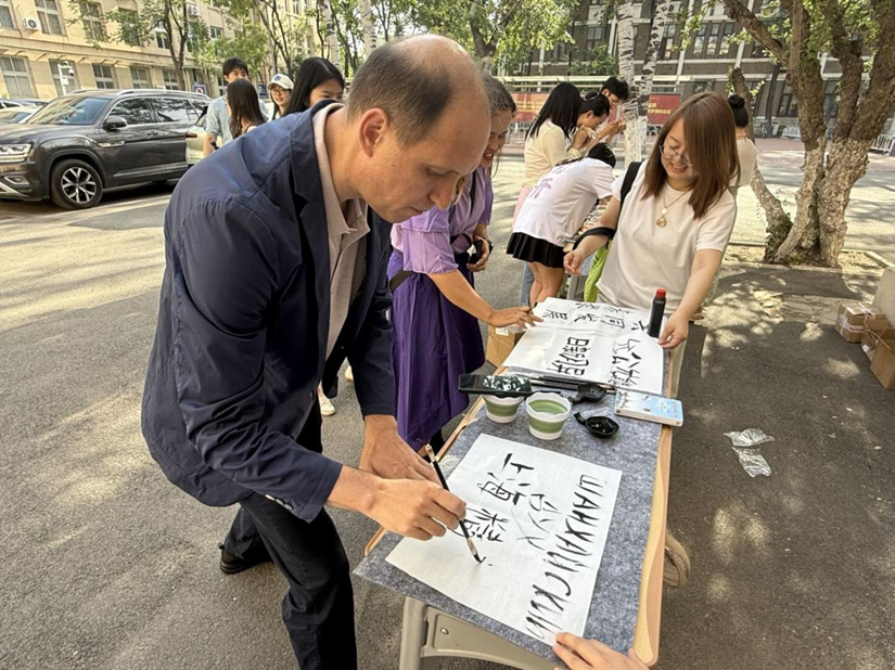 南开大学举办“语通上合 · 戏汇丝路”主题活动_fororder_俄罗斯籍教师谢尔盖正在用毛笔书写“上海精神”
