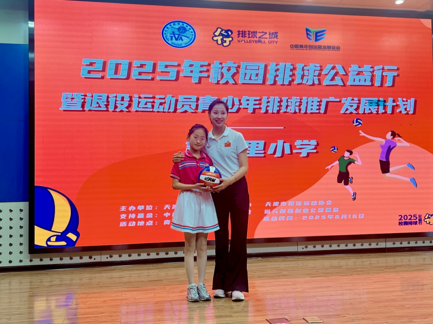 燃动排球梦！天津女排退役名将走进育婴里小学 传承女排精神_fororder_天津市排球运动管理中心副主任王茜向育婴里小学同学赠送排球